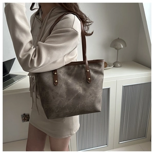 Dettaglio della borsa tote grigia vintage con manici in pelle marrone e rivetti dorati