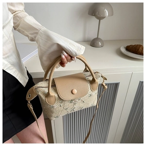 Detail of woven straw bag featuring white floral embroidery and khaki leather trim