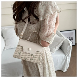Detail van bloemenborduurwerk op een minimalistische patchwork crossbodytas van leer