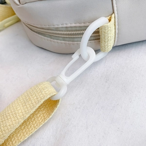 Off-white nylon crossbody bag featuring woven yellow strap and plastic buckle detail