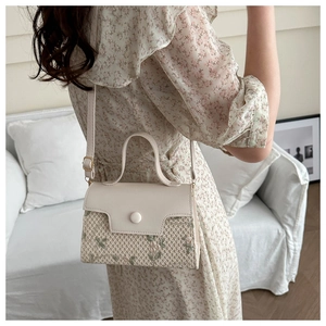 Detail van geweven leren crossbodytas met bloemenborduursel en verstelbare riem