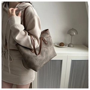 Dettaglio di borsa tote vintage in tela con manici in pelle e rivetti dorati