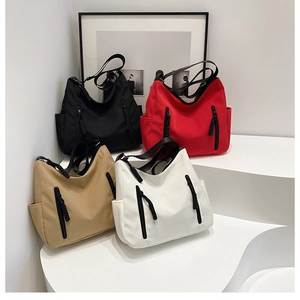 Group of four large capacity tote bags in black, red, khaki, and white on minimalist steps