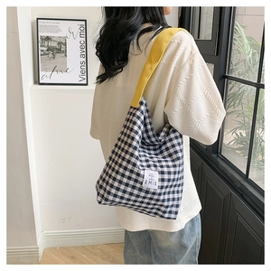 Detail of checkered canvas tote bag with yellow strap and branded woven label