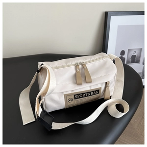 Detail of off-white sports crossbody bag showing XM patch and dual zipper pockets