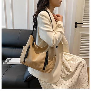 Khaki nylon tote bag with black zipper detail and strap shown worn by a model