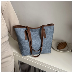 Dettaglio della borsa tote grigio-blu con tela testurizzata e manici in pelle marrone