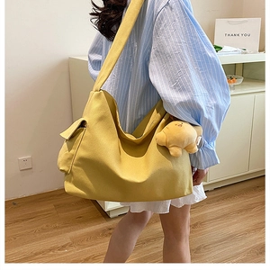 Detail of yellow canvas tote bag with side flap pocket and star plush pendant