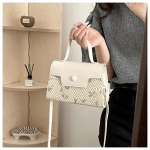 Detail of white leather and green floral woven embroidery on a luxury crossbody bag