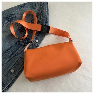 Close-up of orange waterproof nylon crossbody bag with wide strap and plastic buckle