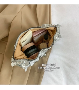 Spacious interior of silver sequin shoulder bag showing storage for phone and perfume