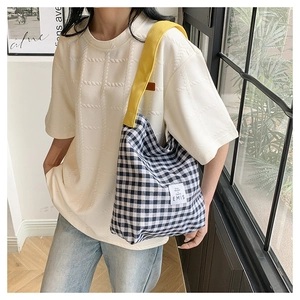 Detail of vintage gingham tote bag featuring bright yellow shoulder straps and woven label