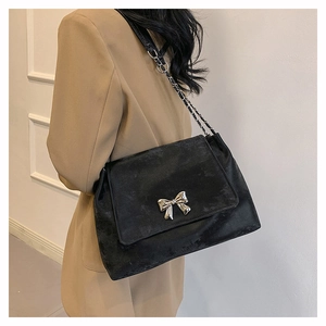 Detail of black bow shoulder bag with silver metallic hardware and chain strap