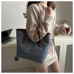 Dettaglio borsa tote in tela blu navy con manici in pelle marrone e borchie dorate