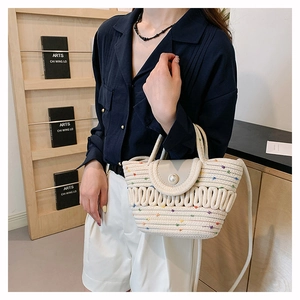 Detail of French knit bag with pearl button closure and woven handles in interior setting