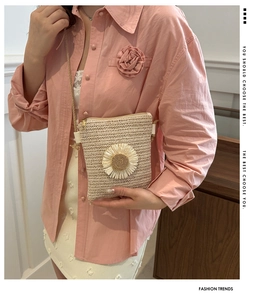 Detail of straw woven crossbody bag featuring a large sunflower accent and rope strap