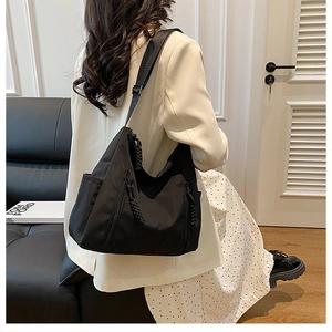 Detailed view of the black tote bag with shoulder strap and side zipper on model