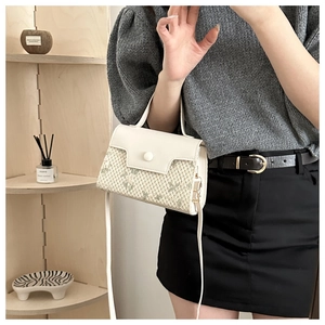 Detail of white leather and beige woven crossbody bag with green floral embroidery texture