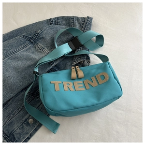Detail of lake blue oxford crossbody bag with TREND leather patch and wide woven strap
