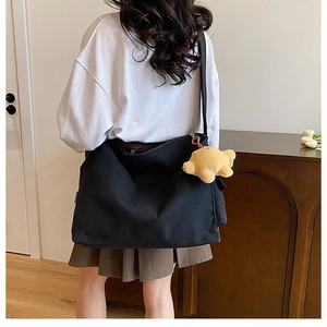 Detail of black canvas crossbody bag with yellow star plush charm in a home setting