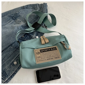 Detail of mint green sports messenger bag featuring retro patch and adjustable strap