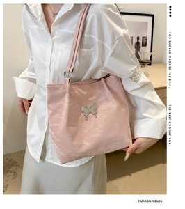 Close-up of pink tote bag with silver butterfly ornament and pleated leather texture