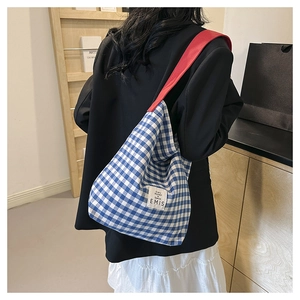 Close-up of blue and white checkered canvas tote with red shoulder strap and EMIS label