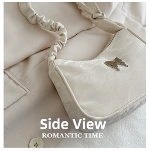 Detail view of a cream shoulder bag featuring a silver butterfly clasp and ruched strap