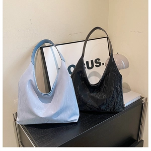 Detail of light blue and black tote bags with pleated texture on a modern wooden table