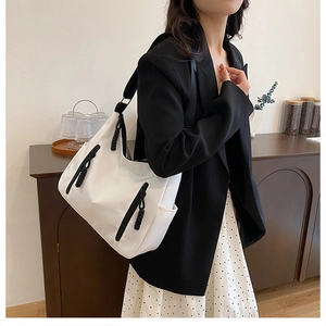 Close-up of white nylon tote bag with black rope zip detail on model in casual style