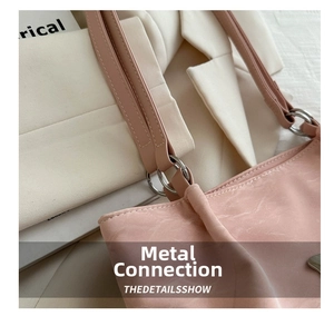 Vue macro du sac à bandoulière rose en similicuir souple avec texture moirée et anneaux argent