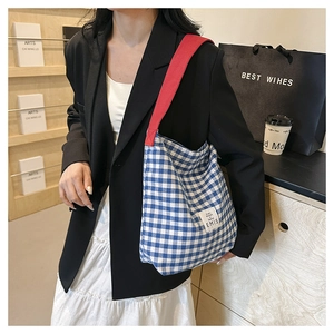 Blue and white checkered canvas tote bag with red shoulder strap and logo detail