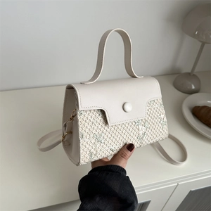 Chic woven straw handbag with green floral embroidery and creamy white leather accents