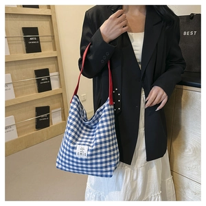 Detail of blue and white gingham canvas tote bag with red strap and EMIS label