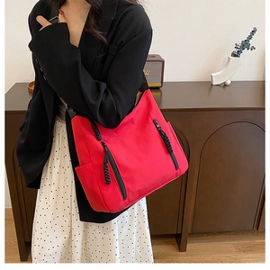 Detail of red hobo tote bag featuring black woven zipper pulls and a functional side pocket