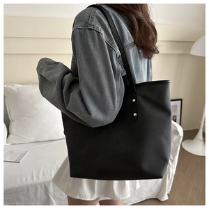 Dettaglio borsa tote nera opaca con borchie dorate decorative sulla tracolla
