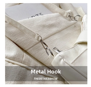 Close-up of sleek silver metal hook and premium beige leather strap on handbag