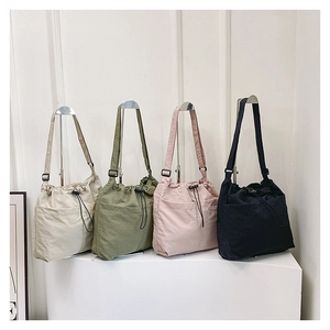 Detail view of four drawstring tote bags in cream, olive, pink, and black colors