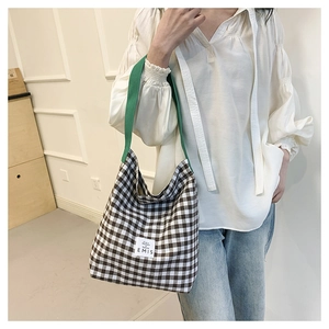 Detail of checkered canvas bucket bag with vibrant green shoulder strap and EMIS logo