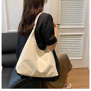 Detail view of large cream tote bag showing soft leather pleats and shoulder strap texture
