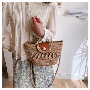Close-up of handmade straw tote with colorful dots and large pearl closure detail