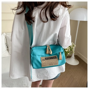 Detail shot of cyan canvas sports crossbody bag with adjustable strap and woven label