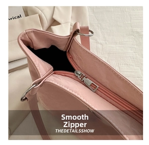Détail de la fermeture éclair en métal argenté sur un sac à épaule en cuir rose pastel