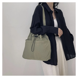 Detail view of olive green drawstring tote bag showing durable nylon texture and pockets