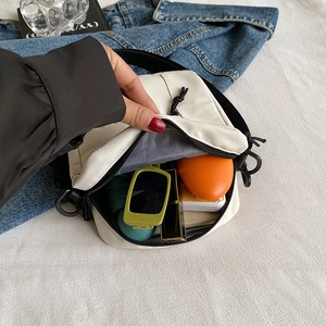 White mini canvas crossbody bag showing interior capacity with sunglasses and accessories