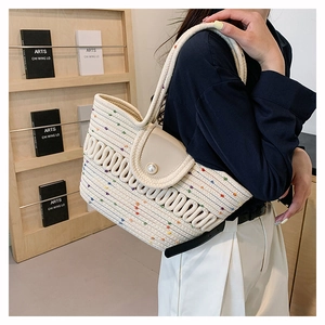 Detail of hand-woven straw tote bag with colorful specks and elegant pearl button closure