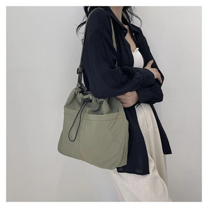 Detail view of large olive green nylon bucket bag with drawstring closure and front pocket