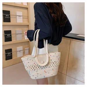 Detail of woven straw tote bag with pearl button closure and colorful dot accents