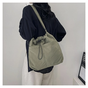 Detail of olive green drawstring bucket bag showing large pockets and nylon texture