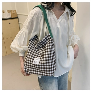 Detail of checkered canvas tote bag with green straps and EMIS brand label on side